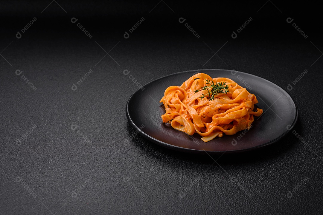 Deliciosa massa fresca com molho pesto, sal, especiarias e ervas num prato cerâmico sobre um fundo de concreto texturizado