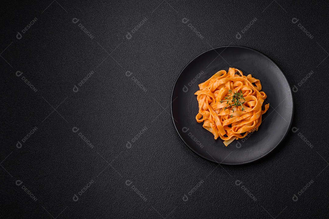 Deliciosa massa fresca com molho pesto, sal, especiarias e ervas num prato cerâmico sobre um fundo de concreto texturizado