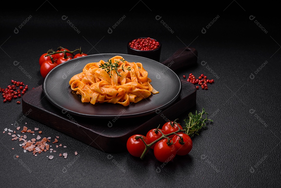 Deliciosa massa fresca com molho pesto, sal, especiarias e ervas num prato cerâmico sobre um fundo de concreto texturizado