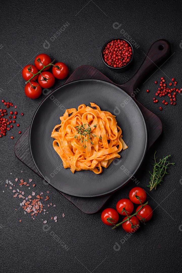 Deliciosa massa fresca com molho pesto, sal, especiarias e ervas num prato cerâmico sobre um fundo de concreto texturizado