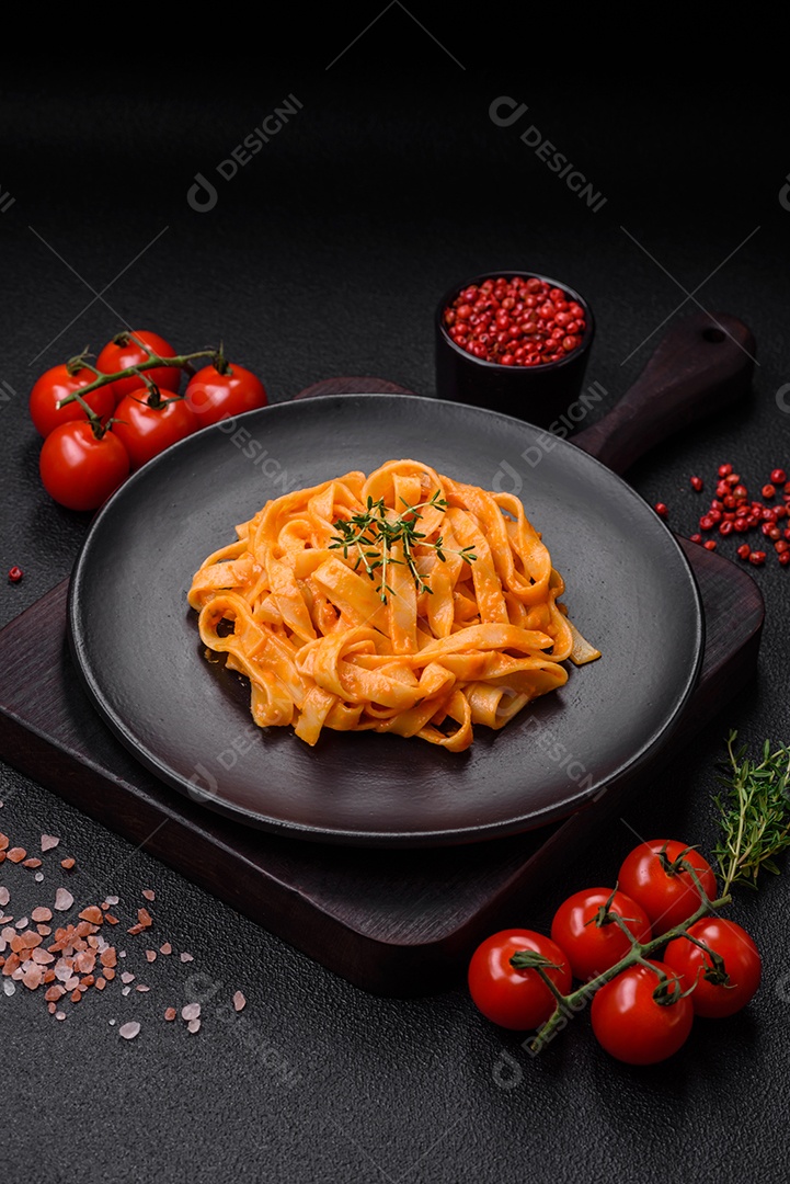 Deliciosa massa fresca com molho pesto, sal, especiarias e ervas num prato cerâmico sobre um fundo de concreto texturizado