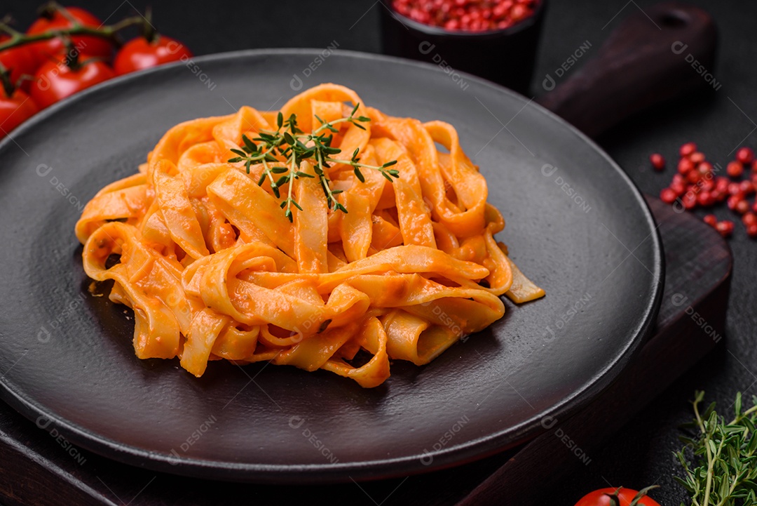 Deliciosa massa fresca com molho pesto, sal, especiarias e ervas num prato cerâmico sobre um fundo de concreto texturizado