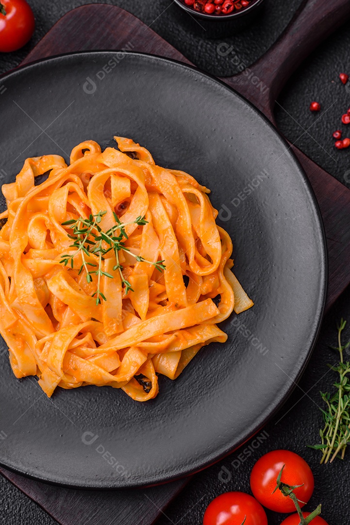 Deliciosa massa fresca com molho pesto, sal, especiarias e ervas num prato cerâmico sobre um fundo de concreto texturizado