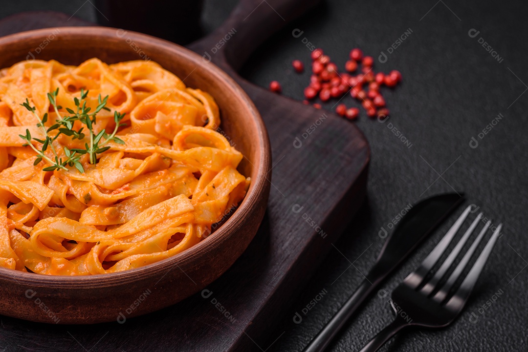 Deliciosa massa fresca com molho pesto, sal, especiarias e ervas num prato cerâmico sobre um fundo de concreto texturizado