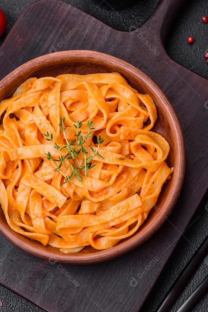 Deliciosa massa fresca com molho pesto, sal, especiarias e ervas num prato cerâmico sobre um fundo de concreto texturizado