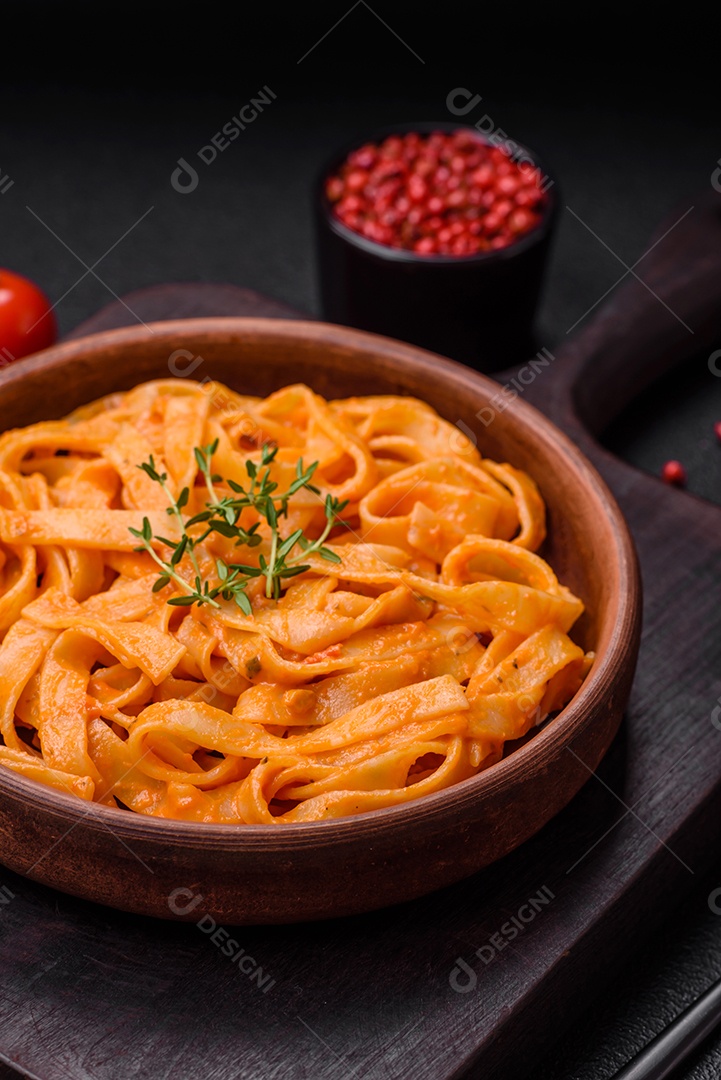 Deliciosa massa fresca com molho pesto, sal, especiarias e ervas num prato cerâmico sobre um fundo de concreto texturizado