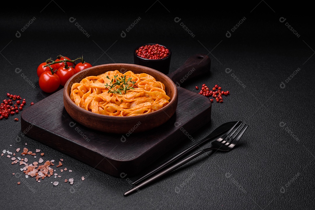 Deliciosa massa fresca com molho pesto, sal, especiarias e ervas num prato cerâmico sobre um fundo de concreto texturizado