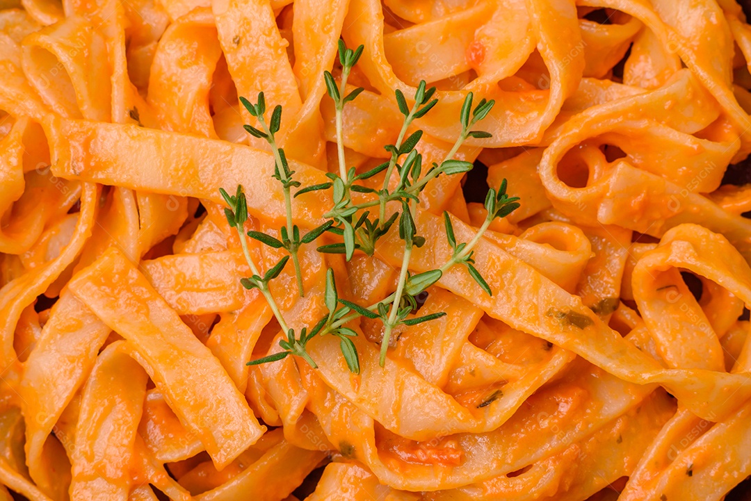 Deliciosa massa fresca com molho pesto, sal, especiarias e ervas num prato cerâmico sobre um fundo de concreto texturizado