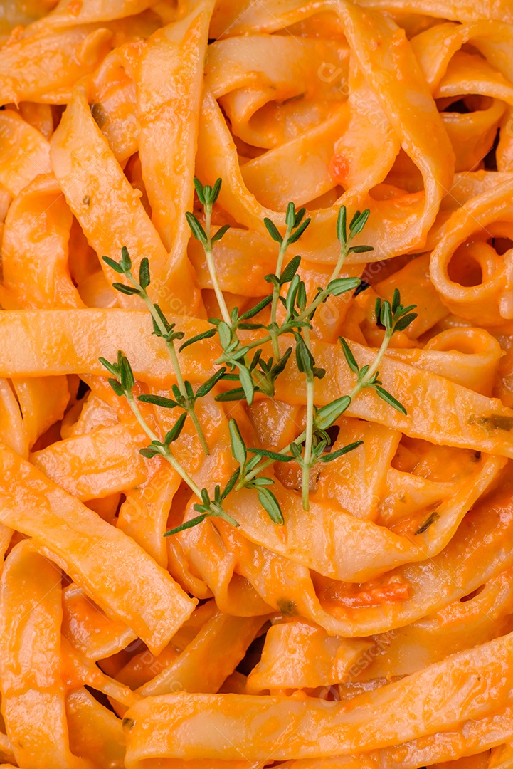 Deliciosa massa fresca com molho pesto, sal, especiarias e ervas num prato cerâmico sobre um fundo de concreto texturizado