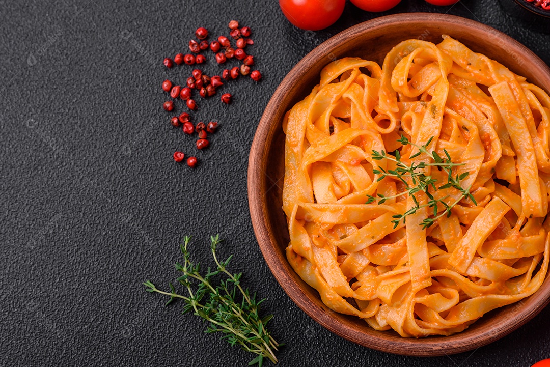 Deliciosa massa fresca com molho pesto, sal, especiarias e ervas num prato cerâmico sobre um fundo de concreto texturizado