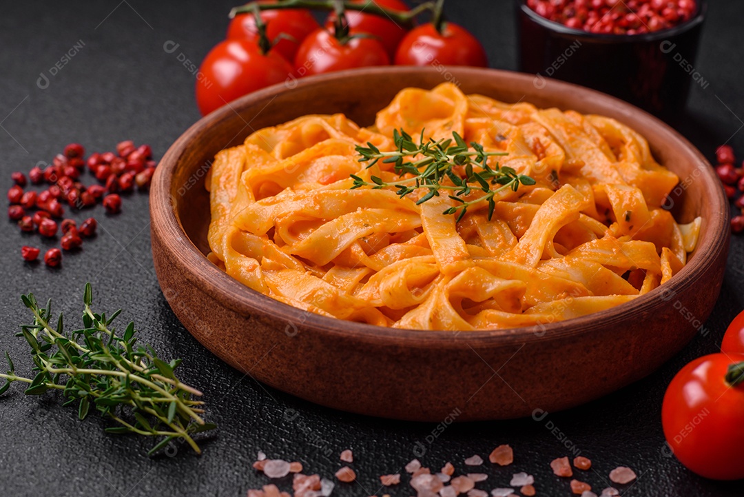 Deliciosa massa fresca com molho pesto, sal, especiarias e ervas num prato cerâmico sobre um fundo de concreto texturizado