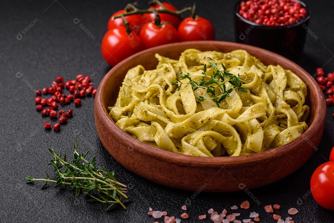 Deliciosa massa fresca com molho pesto, sal, especiarias e ervas num prato cerâmico sobre um fundo de concreto texturizado