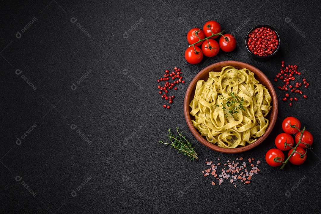 Deliciosa massa fresca com molho pesto, sal, especiarias e ervas num prato cerâmico sobre um fundo de concreto texturizado