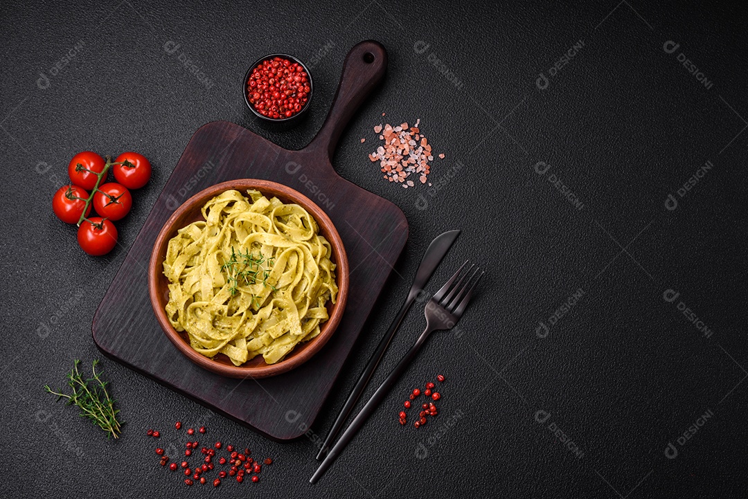 Deliciosa massa fresca com molho pesto, sal, especiarias e ervas num prato cerâmico sobre um fundo de concreto texturizado