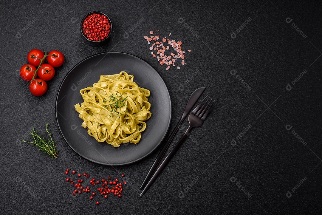 Deliciosa massa fresca com molho pesto, sal, especiarias e ervas num prato cerâmico sobre um fundo de concreto texturizado