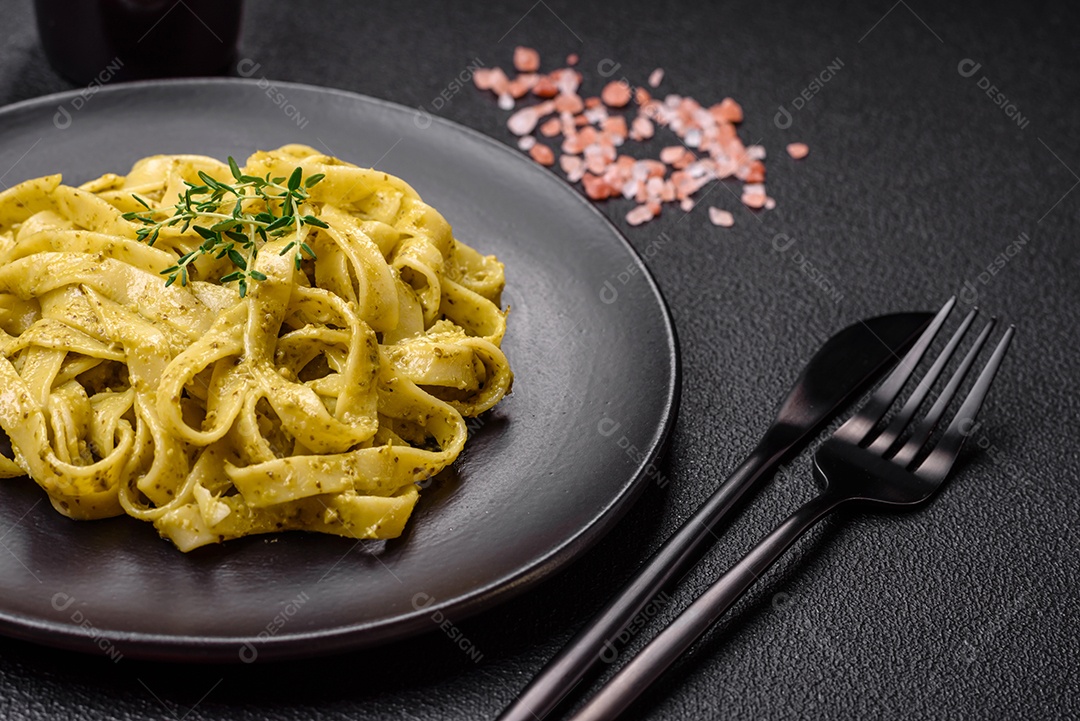 Deliciosa massa fresca com molho pesto, sal, especiarias e ervas num prato cerâmico