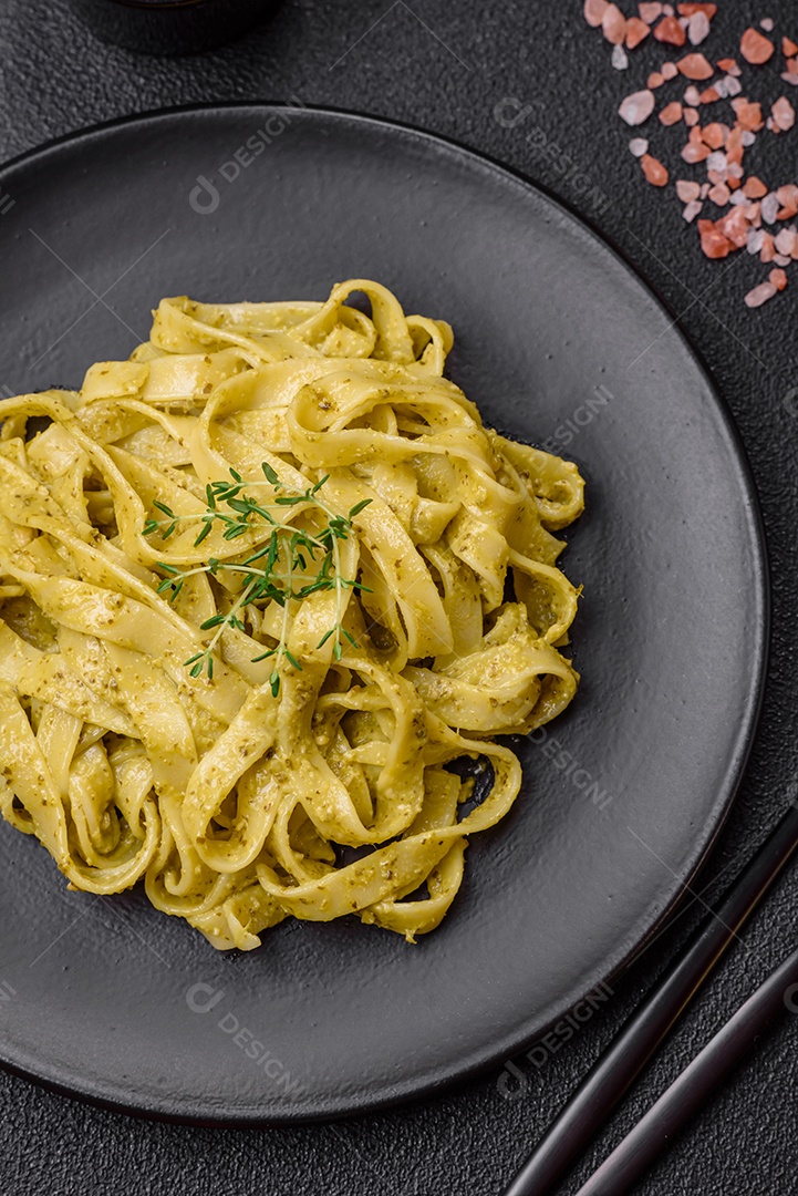 Deliciosa massa fresca com molho pesto, sal, especiarias e ervas num prato cerâmico