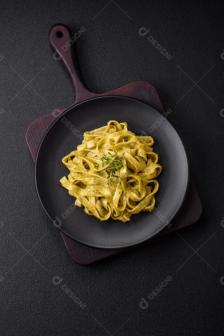 Deliciosa massa fresca com molho pesto, sal, especiarias e ervas num prato cerâmico