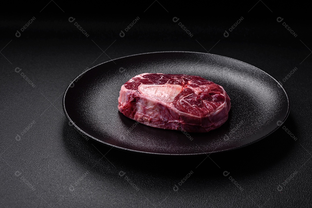 Bife de ossobuco de carne fresca com sal, especiarias e ervas em fundo de concreto texturizado