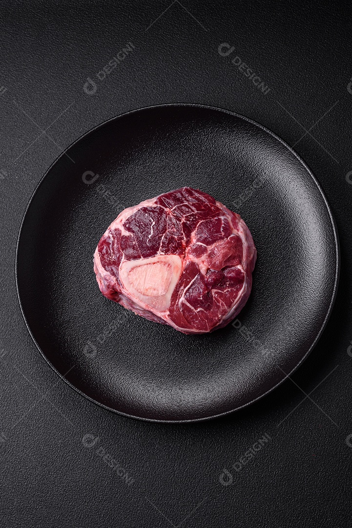 Bife de ossobuco de carne fresca com sal, especiarias e ervas em fundo de concreto texturizado