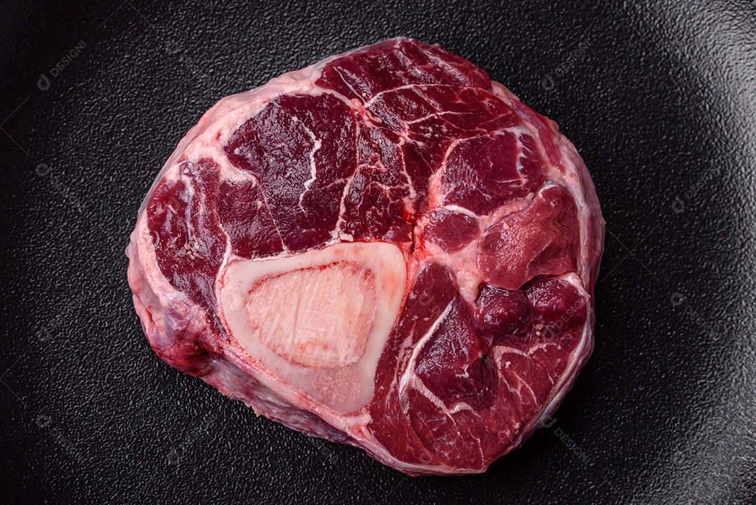 Bife de ossobuco de carne fresca com sal, especiarias e ervas em fundo de concreto texturizado