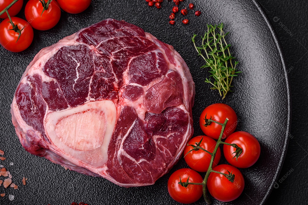 Bife de ossobuco de carne fresca com sal, especiarias e ervas em fundo de concreto texturizado