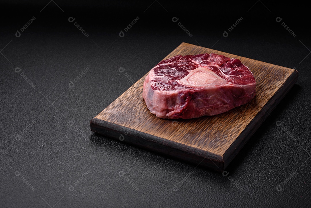 Bife de ossobuco de carne fresca com sal, especiarias e ervas em fundo de concreto texturizado