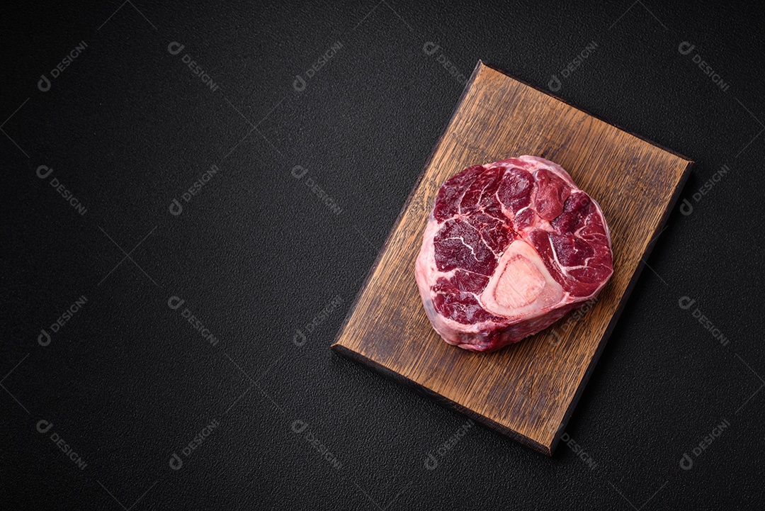 Bife de ossobuco de carne fresca com sal, especiarias e ervas em fundo de concreto texturizado