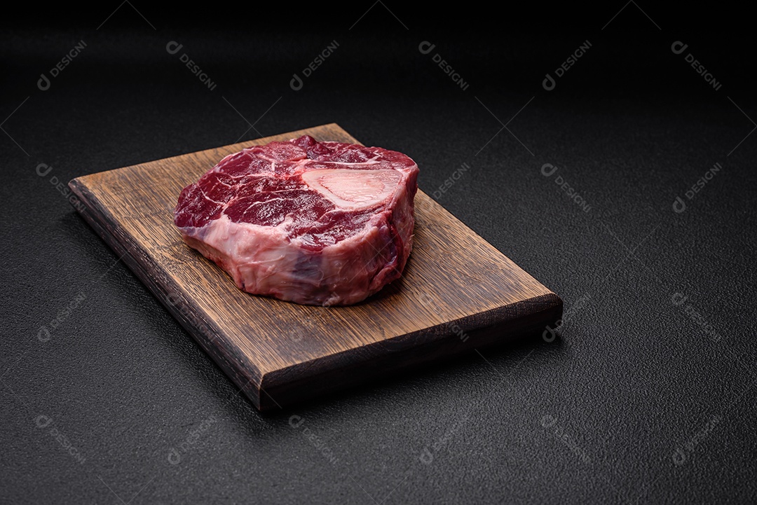 Bife de ossobuco de carne fresca com sal, especiarias e ervas em fundo de concreto texturizado