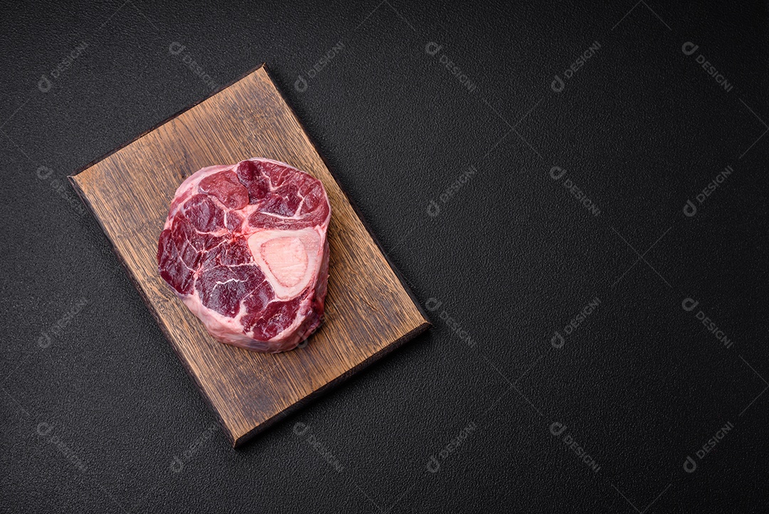 Bife de ossobuco de carne fresca com sal, especiarias e ervas em fundo de concreto texturizado