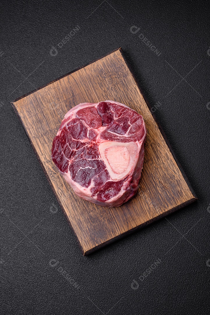 Bife de ossobuco de carne fresca com sal, especiarias e ervas em fundo de concreto texturizado