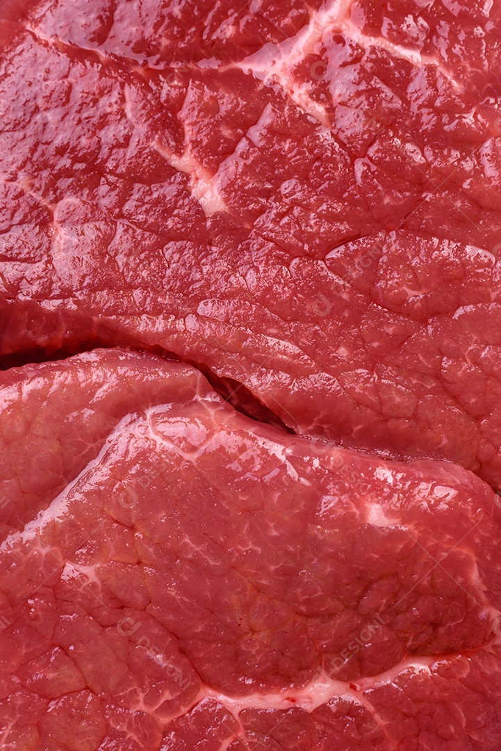 Bife de filé mignon cru com sal, especiarias e ervas em um fundo escuro de concreto