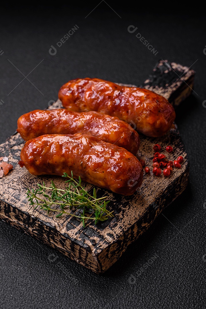 Deliciosos enchidos de frango ou porco grelhados com sal, especiarias e ervas sobre um fundo escuro de concreto