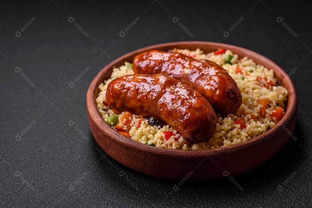 Deliciosas salsichas de frango ou porco assadas na grelha e cuscuz com legumes sobre um fundo escuro de concreto