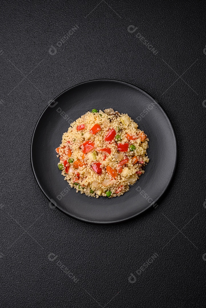 Delicioso cuscuz com cubos de legumes grelhados com sal e especiarias sobre um fundo escuro de concreto