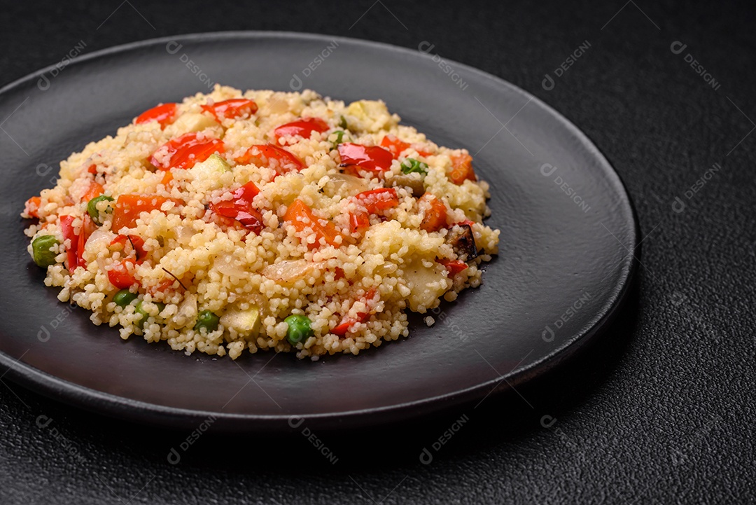 Delicioso cuscuz com cubos de legumes grelhados com sal e especiarias sobre um fundo escuro de concreto