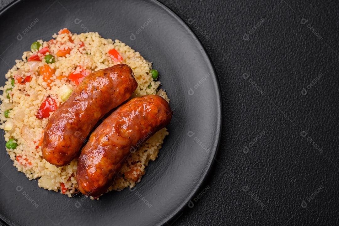 Deliciosas salsichas de frango ou porco assadas na grelha com mingau e legumes sobre um fundo escuro de concreto