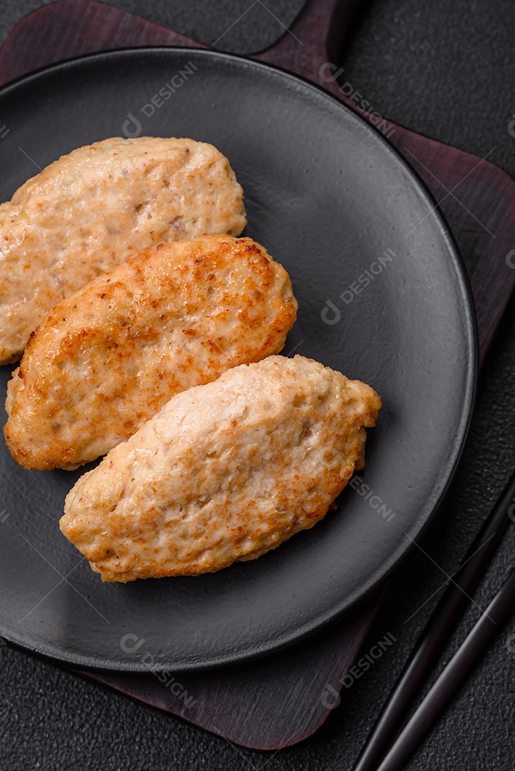 Deliciosa costeleta de frango frito ou carne de porco frita à milanesa com sal, especiarias e ervas sobre um fundo escuro de concreto