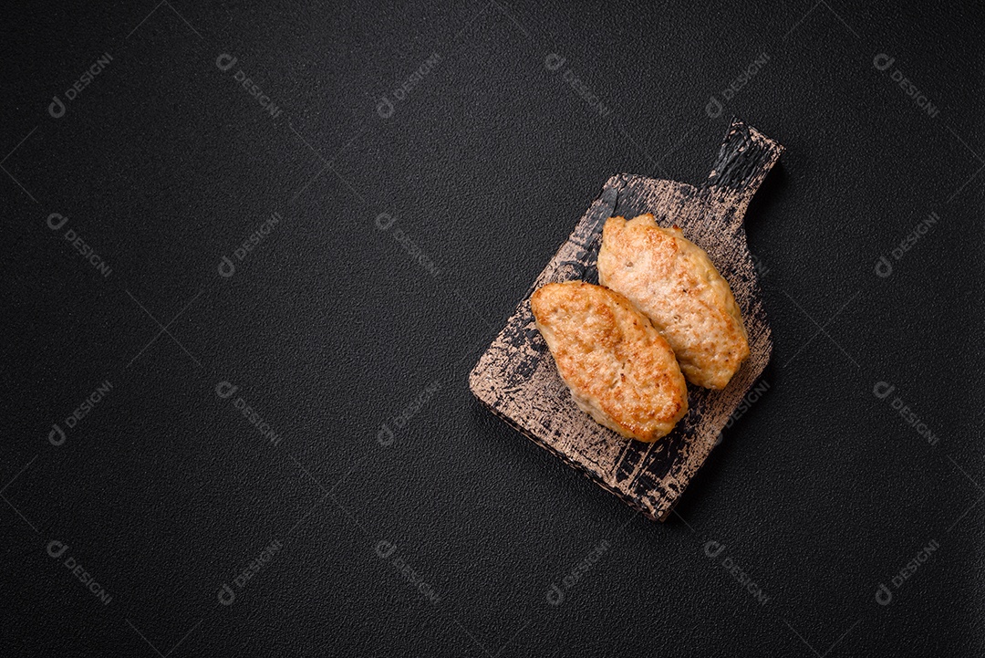 Deliciosas costeletas suculentas ou almôndegas de frango picado com sal e especiarias sobre um fundo de concreto texturizado