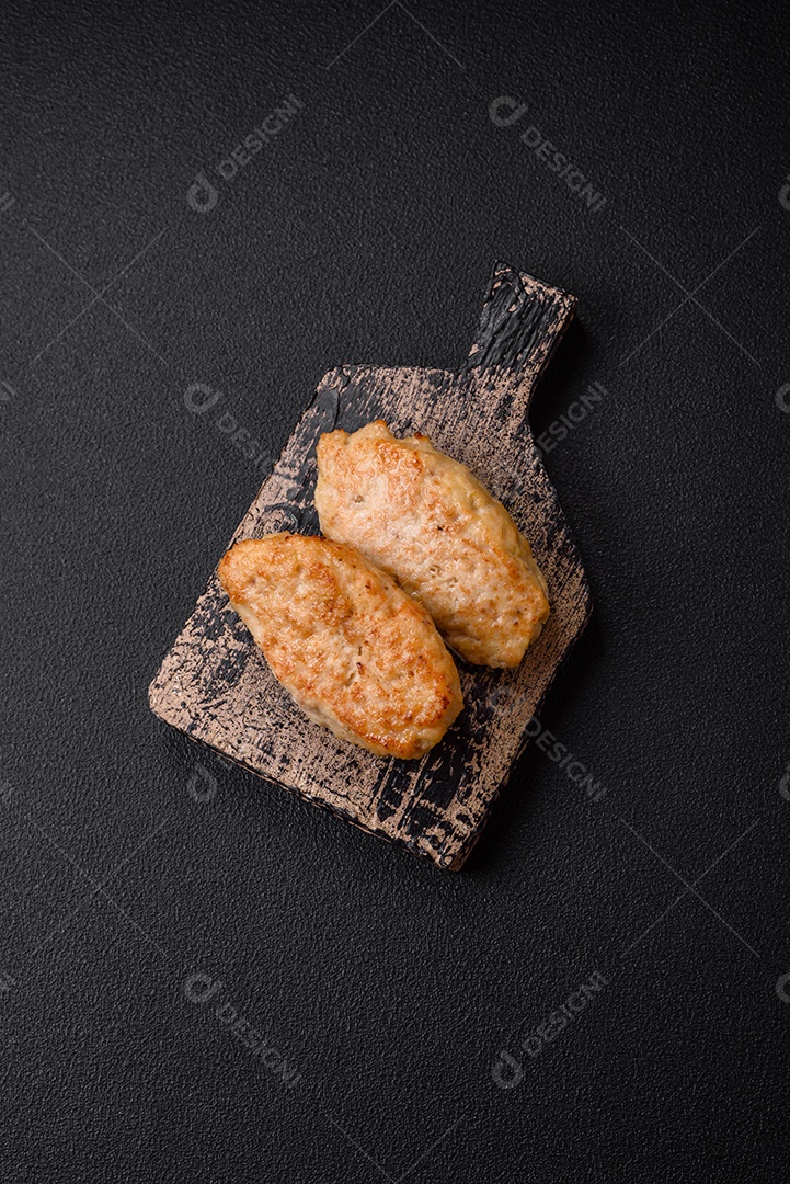 Deliciosas costeletas suculentas ou almôndegas de frango picado com sal e especiarias sobre um fundo de concreto texturizado