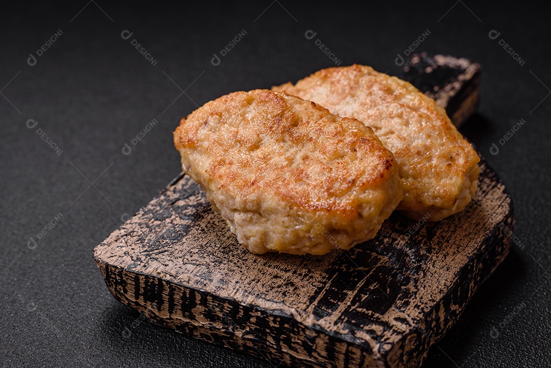 Deliciosas costeletas suculentas ou almôndegas de frango picado com sal e especiarias sobre um fundo de concreto texturizado