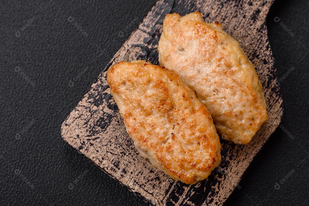 Deliciosas costeletas suculentas ou almôndegas de frango picado com sal e especiarias sobre um fundo de concreto texturizado