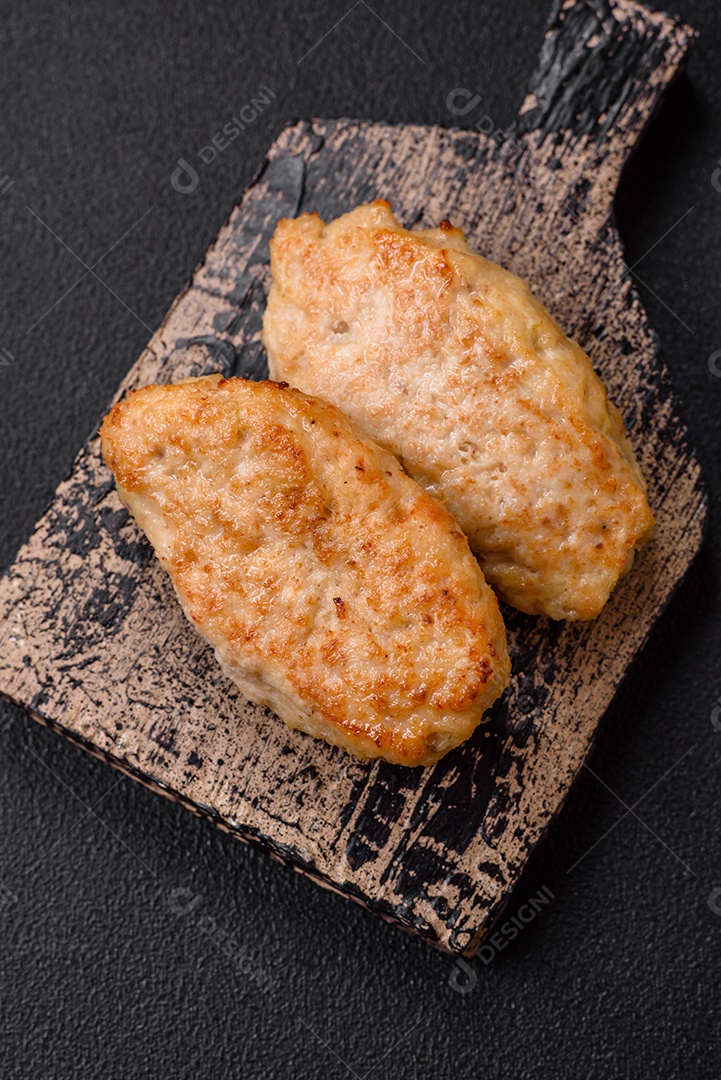 Deliciosas costeletas suculentas ou almôndegas de frango picado com sal e especiarias sobre um fundo de concreto texturizado