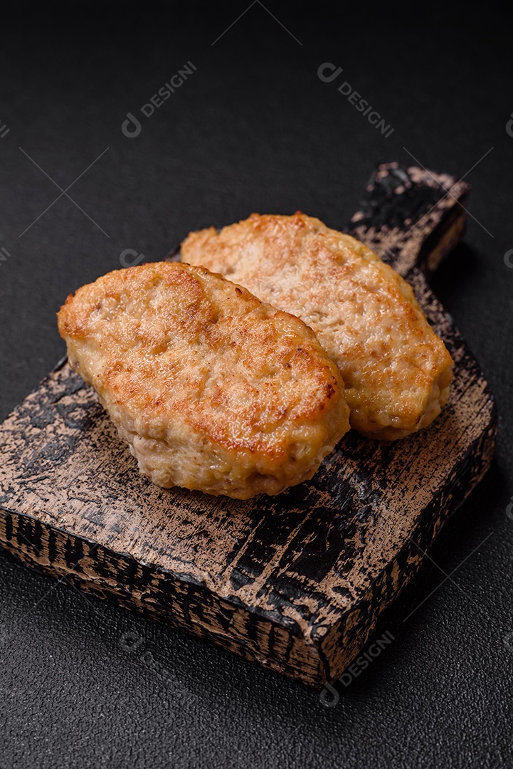 Deliciosas costeletas suculentas ou almôndegas de frango picado com sal e especiarias sobre um fundo de concreto texturizado