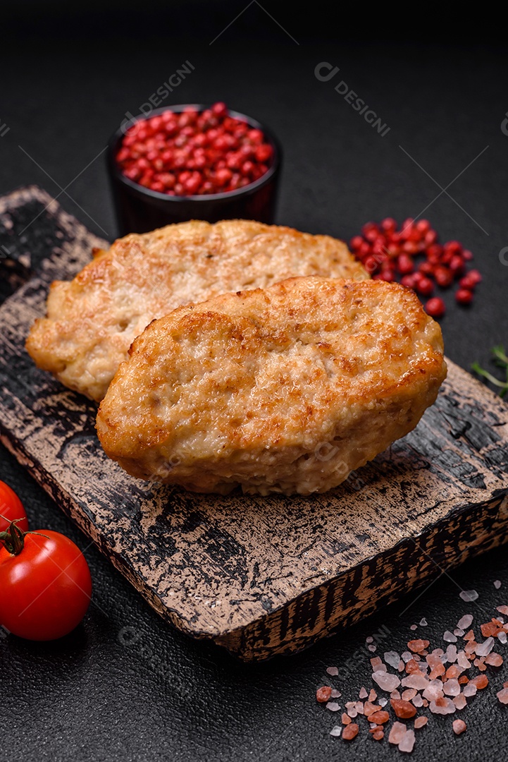 Deliciosas costeletas suculentas ou almôndegas de frango picado com sal e especiarias sobre um fundo de concreto texturizado