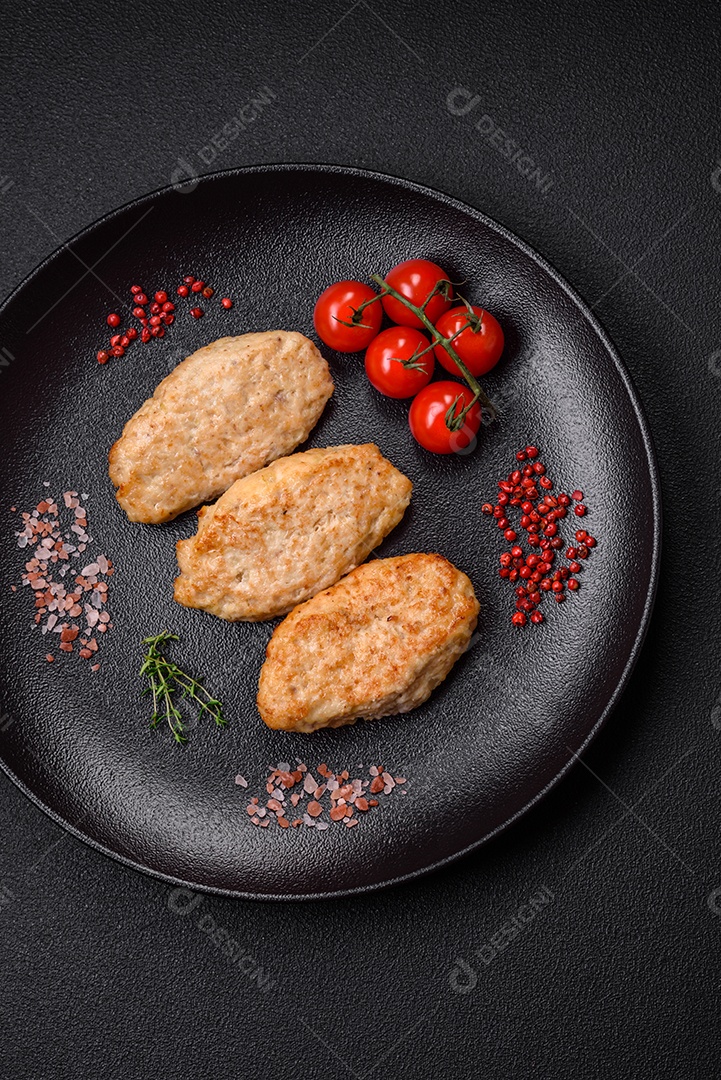 Deliciosa costeleta de frango frito ou carne de porco frita à milanesa com sal, especiarias e ervas sobre um fundo escuro de concreto