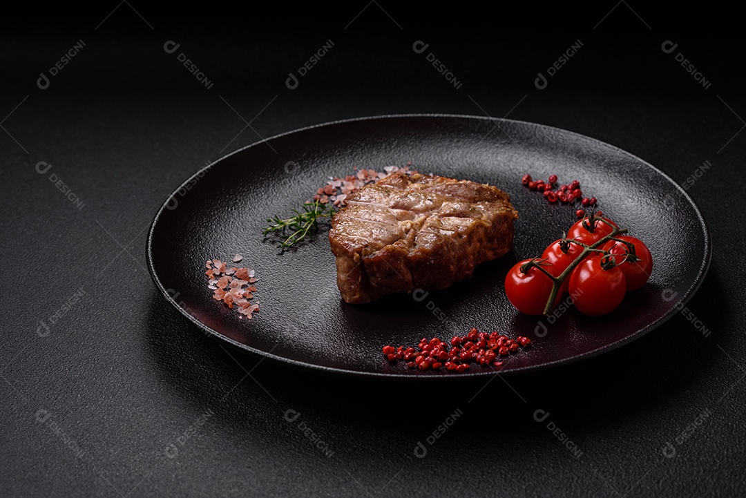 Delicioso suculento bife de porco ou de vaca cozido na grelha com sal e especiarias sobre um fundo de concreto texturizado