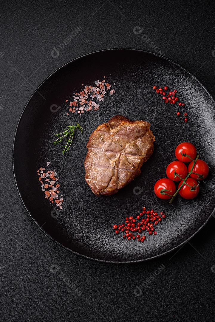 Delicioso suculento bife de porco ou de vaca cozido na grelha com sal e especiarias sobre um fundo de concreto texturizado