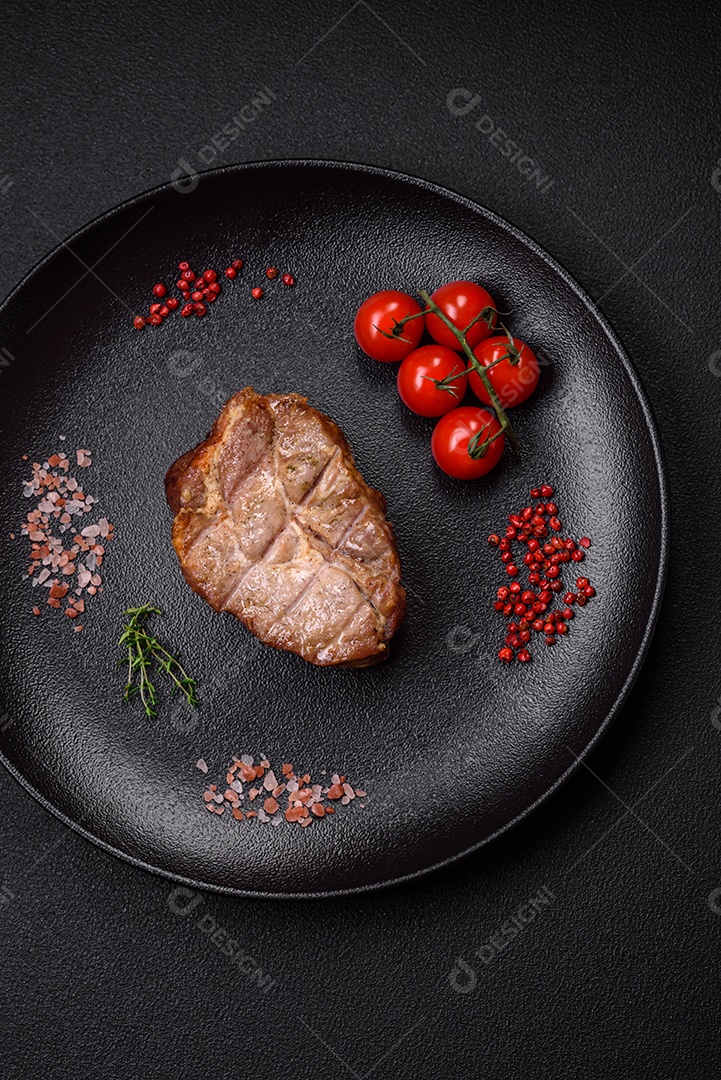 Delicioso suculento bife de porco ou de vaca cozido na grelha com sal e especiarias sobre um fundo de concreto texturizado