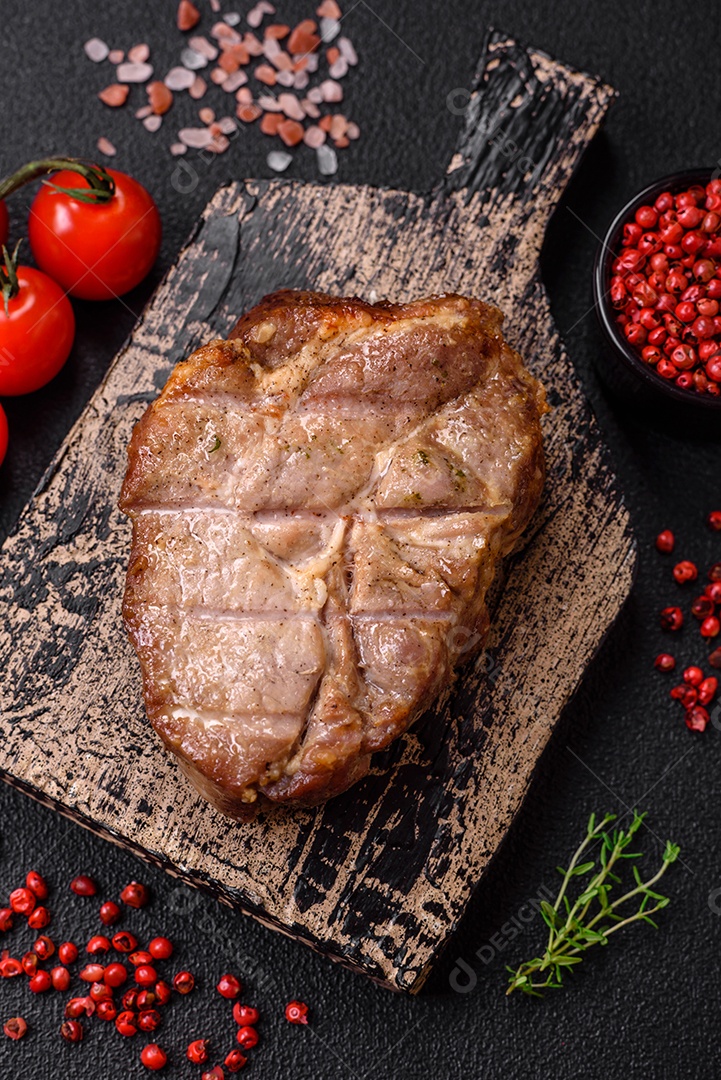 Delicioso suculento bife de porco ou de vaca cozido na grelha com sal e especiarias sobre um fundo de concreto texturizado